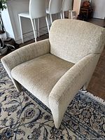 Front-left angle of the armchair showing seat cushion, armrests, and integrated legs