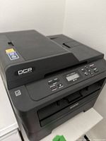 Front and angled top view of the Brother multifunction printer showing control panel and paper tray.