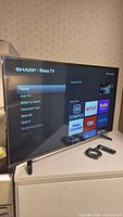 43-inch Sharp Roku TV powered on showing home screen with apps like Netflix, Roku Channel, Crave, CNN.