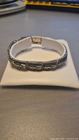 Sterling silver Art Deco style bracelet with marcasite inlay shown on a cushion, displaying front and side views to highlight design and condition.