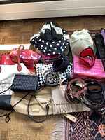 Wide view of the entire lot showing various hats including a black and white polka dot bucket hat, white baseball cap, and several purses and belts placed on a patterned rug.