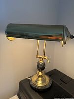 Full side angle view of the lamp showing green glass shade and brass arms.