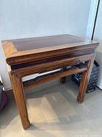Side view of wooden accent table showing carved floral detail and stretcher bar among legs