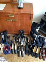 All women's shoes in good condition, various styles, all size 10.5, arranged on the floor near a wooden cabinet.