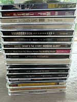 Stack of 24 audio CDs showing spines with artist names and album titles such as Barenaked Ladies, Oasis, Soundgarden, The Cranberries, Michael Bublé, R.E.M., The Verve, and others.