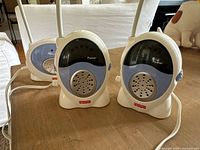 Photo of two portable receiver units with white stands and blue and white casing, placed on wooden floor