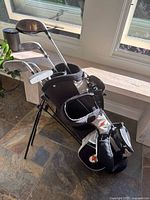 Full view of the youth golf stand bag with clubs inserted, showing bag design, dual backpack straps, and club heads visible.
