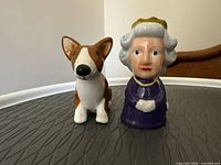 Front view of the queen and corgi ceramic salt and pepper shakers on textured round surface.