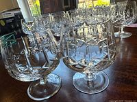 Two cut crystal brandy snifter glasses on table showing distinct cut glass patterns, one with star-like pattern and the other with geometric pattern.