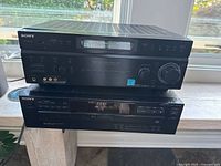 Stacked Sony stereo receiver on top and 5-disc CD player below, showing front panels and digital displays.