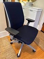 Front three-quarter view of cobalt blue Steelcase Think chair with silver frame on hardwood floor