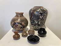 Front view of the full Southwest pottery collection showing all seven vessels grouped on a white pedestal.