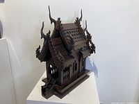 Angled front and side view showing detailed roof carvings and stairs