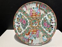 Full face view of the circular Chinese Famille Rose porcelain plate showing overall painted decoration with floral and figure panels.