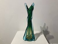 Front and side views of the twisted green and blue Murano glass vase on a white surface.