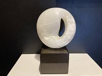 Front view of the white abstract stone sculpture on black base