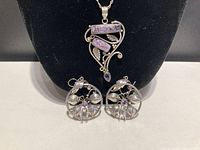 Full set displayed on black velvet background showing pendant centered with two earrings below it.