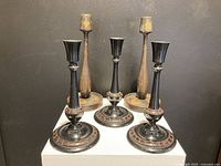 Two sets of turned wood candle holders: two taller natural wood finish and three shorter black with red detailing.