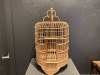 Full view of vintage bamboo bird cage showing cylindrical shape, vertical bamboo slats, and rounded top with handle.