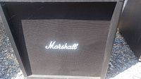 Front of speaker cabinet showing grille cloth and white Marshall logo