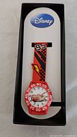 Disney Pixar Cars kids watch in original black and white Disney box. Watch has red strap with checkered pattern and number 95 emblem. Dial shows Lightning McQueen character.