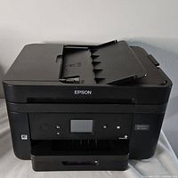 Front view of the Epson WF-2860 printer showing the control panel, paper tray, and top feeder.