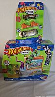 Lot contents photo showing two Hot Wheels Skate toys: skateboard and car set, and Aquarium Skatepark playset in packaging.