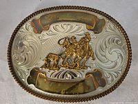 Front view of the large vintage cowboy belt buckle showing detailed silver-tone scrollwork and gold-tone cowboy motif.