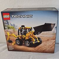 Front side of the LEGO Technic Backhoe Loader box showing set number 42197, 104 pieces, age 7+ recommendation, image of yellow and black backhoe loader model.