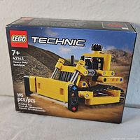 Front view of the Lego Technic Heavy-Duty Bulldozer box showing the set number 42163, recommended age 7+, and 195 pieces.