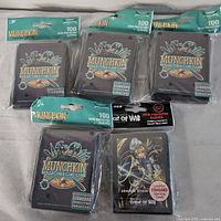 Five packages of deck protector sleeves: four packs of 100 Munchkin sleeves each and one pack of 65 Force of Will sleeves, all new and sealed in original packaging.