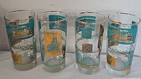 Full view of all four mid century tall glasses with steamboat decorations and gold rims