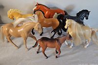Seven toy horses in various colors and materials with different synthethic manes and tails, assorted sizes and poses