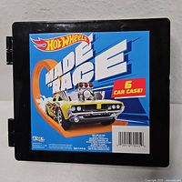 Hot Wheels branded black plastic 6-car case with colorful label showing 'Made to Race' and a yellow muscle car illustration.