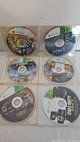 Photo showing six Xbox 360 game discs in plastic cases including recognizable titles Halo Reach, Fallout 3, Call of Duty MW3 and others.