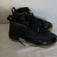 Side angle view of the left and right Nike Jordan sneakers showing the black leather upper and translucent outsoles with wear.