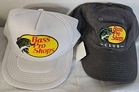 Pair of two Bass Pro Shops trucker hats, one white with tag and one black with Club logo