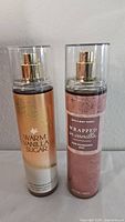 Photo of two Bath & Body Works vanilla scented fragrance mists, new and sealed in clear plastic cases.