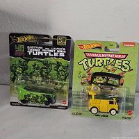 Two sealed Hot Wheels Teenage Mutant Ninja Turtles diecast toy vehicles displayed side by side on a flat surface.