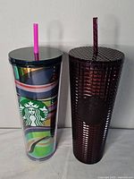 Both Starbucks tumblers side by side, showing one with colorful swirl design and the other dark purple with grid texture.