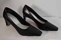 Side angle view of both black high heels showing shape and heel height