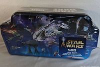 Front side of the Star Wars 500 piece puzzle tin showing vehicle graphics and Star Wars logo.