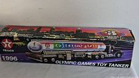 Boxed toy tanker showing Texaco branding with city skyline background, 1996 Olympic Games logo and colorful athlete silhouettes.
