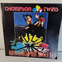 Front cover of the 1984 Thompson Twins North American Tour Program showing band members and colorful design.