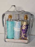 Clear case containing three Tommy Bahama women's body spray bottles with gold and silver spray tops.