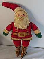 Front view of the full Santa Claus doll showing red suit, green mittens, gold boot details, and red pointed hat