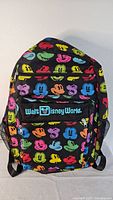 Front view of the large black backpack featuring colorful Mickey Mouse faces and a front zippered pocket with Walt Disney World logo.