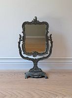 Front view of antique Brevetto mirror on wooden floor, showing entire frame and mirror surface.