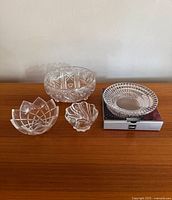 Four crystal and glass bowls and plate displayed together on wooden table, showing detailed cut patterns