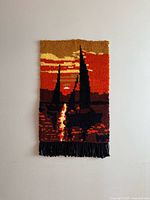 Full view of the tapestry hung on a plain white wall, showing the rich colors and tall abstract shapes design.